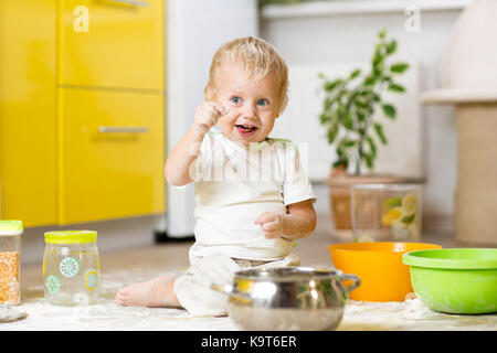 Little child boy playing with kitchenware and foodstuffs in domestic kitchen Stock Photo