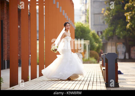 outdoor portrait of young and beautiful asian bride with bouquet in hand. Stock Photo