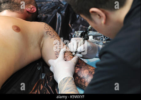 London, UK. 24th September, 2017. A tattooist at work at the the 13th London International Tattoo Convention, which took place over the weekend in Tobacco Dock, east London.  The show features over 400 of the world’s finest, most prestigious and elite tattoo artists as well as showcasing piercing and other aspects of alternative culture. Credit: Michael Preston/Alamy Live News Stock Photo