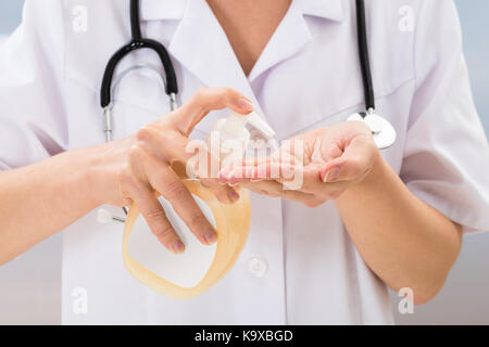 Close-up Of Female Medical Doctor Using Sanitizer Dispenser Stock Photo