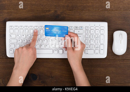 Close-up Of Person Hands With Credit Card And Computer Keyboard At Desk Stock Photo
