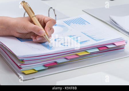 Close-up Of Person Hands With Pen Analyzing Graphs At Desk Stock Photo