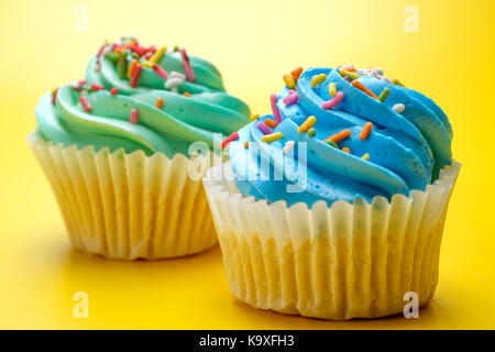 Tasty cupcakes on yellow background, selective focus Stock Photo