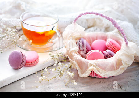 Tea with lemon, wild flowers and macaron on white wooden table. Delicate still life. Stock Photo