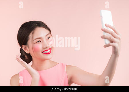 Smiling lovely active asian girl taking selfie photo. Isolated on white