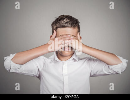 Closeup portrait young male, shy man closing covering eyes with hands can't see, hiding, isolated grey wall background. See no evil concept. Negative  Stock Photo