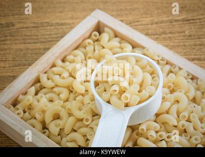 Food and Cuisine, Uncooked and Dried Elbow Macaroni or Gomiti Pasta in Plastic Measuring Cup. Stock Photo