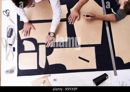 High angle view of concentrated young tailors using sewing patterns while working on creation of custom-made male jacket Stock Photo