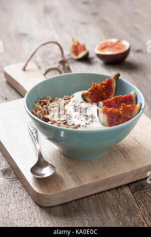 healthy breakfast. muesli, yoghurt, figs, chia seeds in a blue bowl ha old wooden background Stock Photo