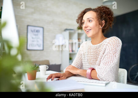 Portrait of smiling mixed-race woman enjoying work from home in modern apartment Stock Photo