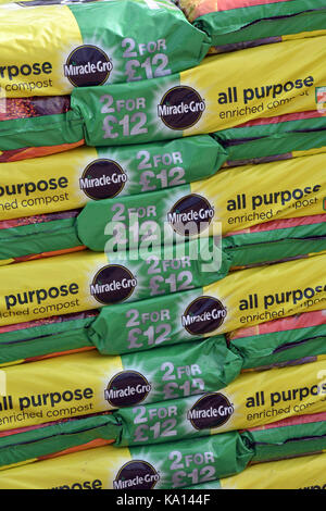 bags of potting compost for sale in a stack or pile of sacks a t a garden centre for potting and planting out plants flowers and vegetables. Stock Photo