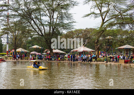 People enjoying peddle boat rides on lake, amusements and fairground can be seen in background, Uhuru Park, Nairobi, Kenya, East Africa Stock Photo