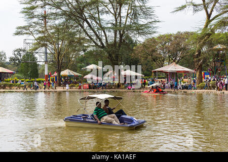 People enjoying peddle boat rides on lake, amusements and fairground can be seen in background, Uhuru Park, Nairobi, Kenya, East Africa Stock Photo