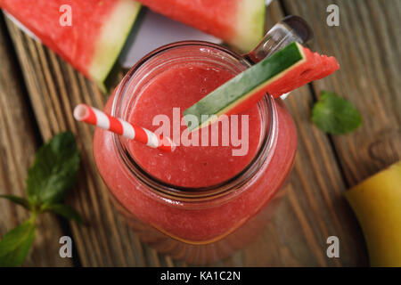 Freshly made smoothies from pieces of watermelon and a banana in a glass jar on a wooden table, top view Stock Photo