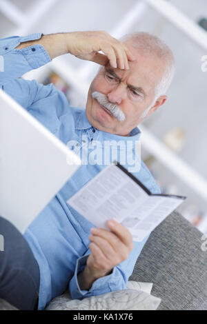 confused old man reading manual at home Stock Photo