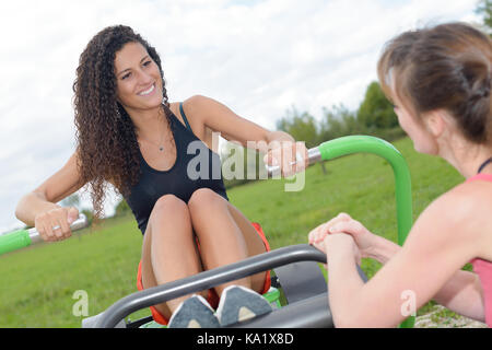 young woman exercising on rowing machine in park Stock Photo