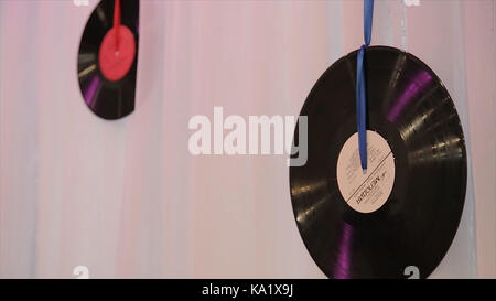 vinyl records hang on the wall with red ribbons. Black vinyl records.Using vinil records like a element of decor Stock Photo