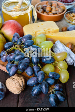 Autumn set of products: grapes, walnuts, hazelnuts, plums, honey, cheese, raisins, pears, dried cranberries on a wooden background Stock Photo