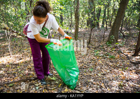 Sofia, Bulgaria - 16 September, 2017: Woman picks up trash in the forest participating in a cleaning campaign. Ecology person cleaning the park. Stock Photo