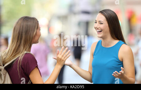 Two happy friends greeting and meeting on the street Stock Photo