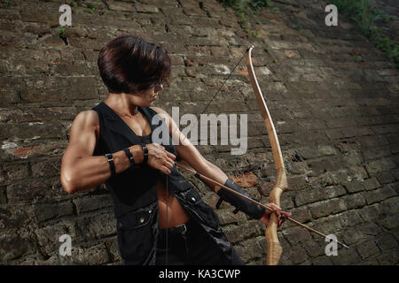 Athletic brunette shooting from bow and tacking focus. Stock Photo