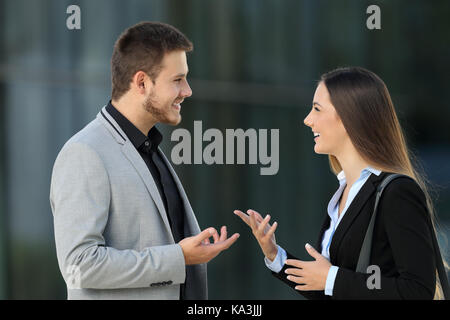 Side view portrait of a happy couple of executives talking on the street Stock Photo