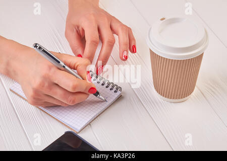 Woman manicured hands writing in notebook. Gentle female hand with beautiful manicure writing with pen in empty notebook. Writing woman hand, paper no Stock Photo