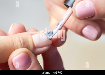 Woman having manicure in beauty salon. Manicure specialist applying varnish on clients nails. Beautician making manicure close up. Stock Photo
