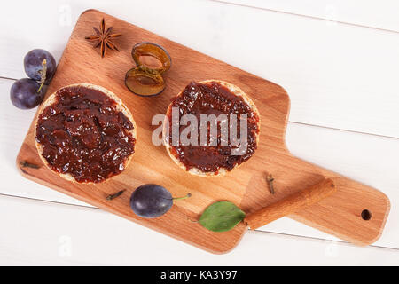 Fresh prepared sandwiches with plum marmalade or jam on wooden cutting board, concept of delicious breakfast Stock Photo