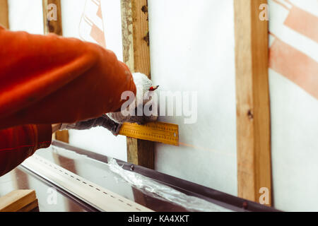 The worker makes measurements when installing the siding Stock Photo