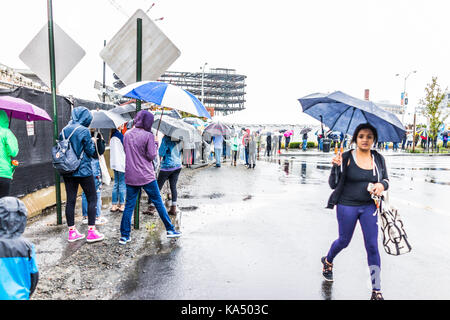 Washington DC, USA - September 2, 2017: People walking and waiting in line queue holding umbrellas during heavy pouring, downpour rain at vegetarian v Stock Photo