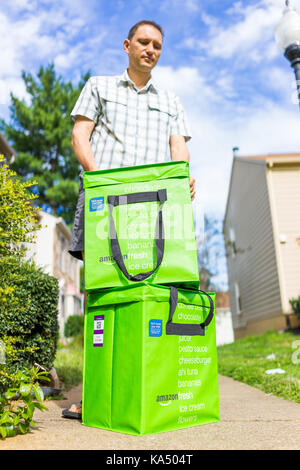 Fairfax, USA - September 12, 2017: Amazon Fresh insulated grocery delivery bags totes on front home house porch closeup with man looking closing lid Stock Photo