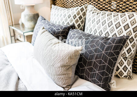 Closeup of new bed comforter with decorative pillows, headboard in bedroom in staging model home, house or apartment Stock Photo