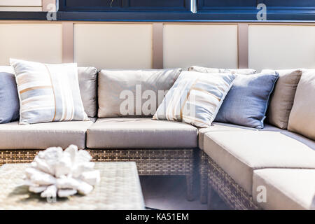 View of comfortable modern corner couch with many pillows outside on loft balcony with bright sun rays Stock Photo