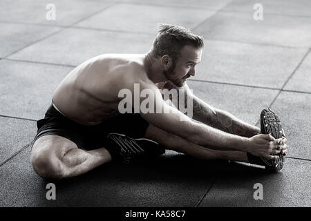 Man Doing Stretching Exercise In Gym Stock Photo