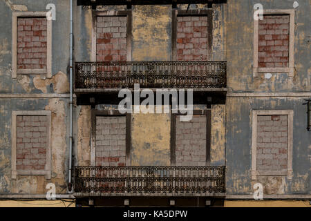 Facade of an old abandoned house in Lisbon, Portugal. Structured facade, former windows filled with bricks. Decorated balconies. Stock Photo