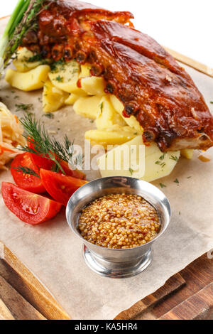 Delicious Grilled Pork Rib and Fried Potato with Sauce and vegetables on wooden cutting board Stock Photo