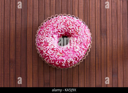 Brightly pink donut on brown wooden background Stock Photo