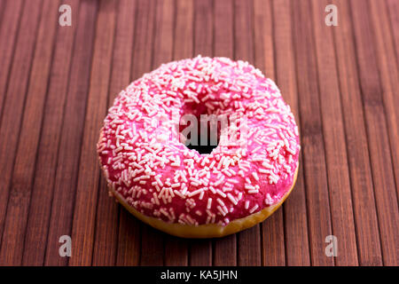 Brightly pink donut on brown wooden background Stock Photo