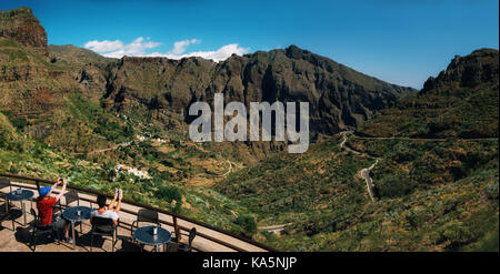 Masca, Tenerife, Canary islands, Spain - May 25, 2017: Panoramic view of Masca valley. Tourists are in cafe on mountain pass and admire Scenic mountai Stock Photo