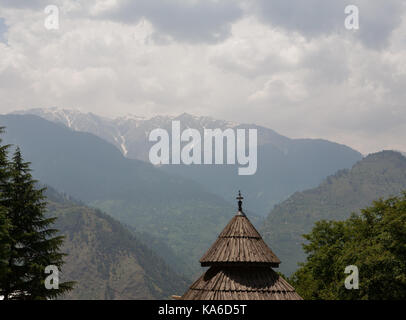 The wooden roof of the Tripura Sundari Temple on the backdrop of Himalayas on a cloudy day. Naggar, district Kullu in Himachal Pradesh, India. Stock Photo