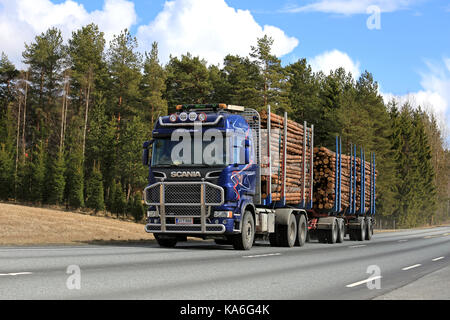 JOKIOINEN, FINLAND - APRIL 23, 2017: Blue Scania logging truck of Aaltonen transports pine timber along highway on a beautiful day of spring. Stock Photo