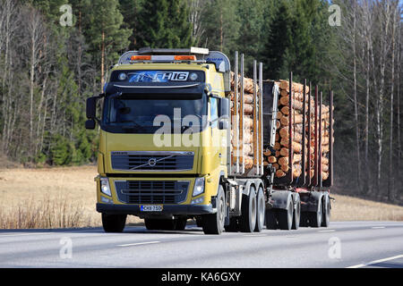 SALO, FINLAND - APRIL 21, 2017: Yellow Volvo FH16 logging truck transports a load of pine logs along highway at spring. Stock Photo