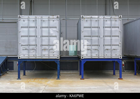 Two Silver Shipping Containers in Front of Warehouse Stock Photo
