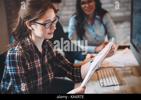 Happy woman in office looking at blueprint Stock Photo