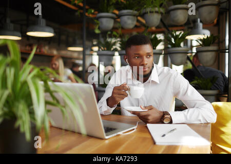 Businessman drinking coffee in cafe resting after work with laptop. Stock Photo