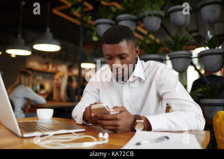 Serious african man chatting, writing message smart phone. Stock Photo