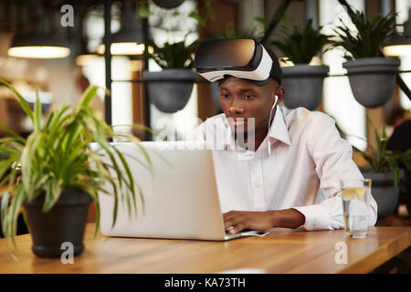African man in head set of virtual reality using laptop. Stock Photo