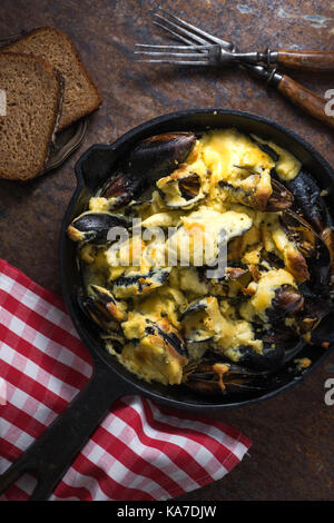 Mussels with cheese sauce in a frying pan, napkin in a red cage vertical Stock Photo