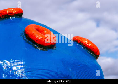 Large blue plastic ball with red buttons on the background of clouds horizontal Stock Photo